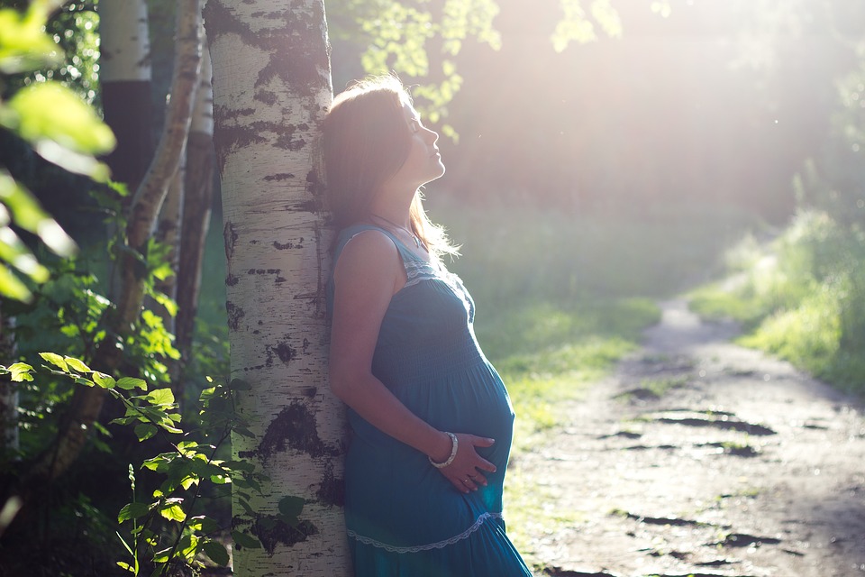 Pregnant woman leaning on tree